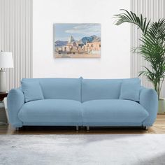 a blue couch sitting in a living room next to a potted plant