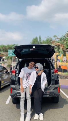 two people standing in the trunk of a car