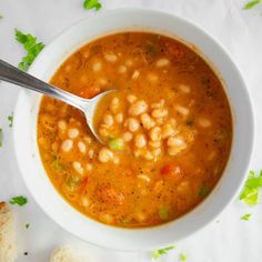 a white bowl filled with soup next to a piece of bread