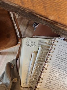 an open book sitting on top of a wooden table next to a pen and paper