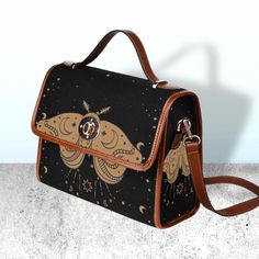 "Witchy moth retro Canvas Satchel bag, moon phase mystical purse, Vegan leather strap boho hippies bag, Witch bag, goth bag, cottagecore bag It's the simple design that makes these Country Life Satchel boho bags the perfect accessory to a boho or Cottagecore / mushroomcore wardrobe. This waterproof canvas with pu leather strap cottagecore crossbody bag is just what you need for a little extra room for your stuff.  Made from quality materials, this cottagecore style boho bag features a secure mag Black Bohemian Shoulder Bag Gift, Gothic Brown Bag For Everyday Use, Vintage Black Shoulder Bag For Festival, Whimsigoth Bag, Black Bohemian Shoulder Bag With Detachable Strap, Black Bohemian Bag With Detachable Strap, Gothic Brown Bag, Bags Cottagecore, Brown Hand Painted Satchel Shoulder Bag