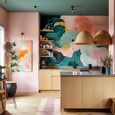 a kitchen with pink walls, wooden cabinets and an art work on the back wall