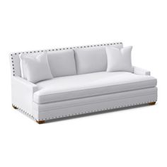 a white couch with studded arms and pillows on it's backrests