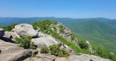 a view from the top of a mountain with rocks and trees in the foreground