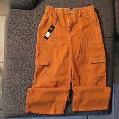 Cargo Pants. High Rise. Color Rust. Looks More Orange In The Picture Than It Actually Is. Has An Elastic Band In The Back On The Waste. Little Stretch. Runs A Little Big. Size:9 Never Worn. Excellent Condition. Relaxed Fit Orange Pants With Pockets, Orange Relaxed Fit Pants With Pockets, Orange Wide Leg Bottoms With Pockets, Orange Cotton Cargo Bottoms, Cotton Cargo Bottoms In Orange, Casual Mid-rise Orange Bottoms, Casual Orange Bottoms With Side Pockets, Casual Orange Bottoms With Pockets, Orange Cotton Bottoms With Pockets