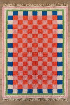 an orange and blue checkered rug with fringes on the bottom, sitting on a wooden floor