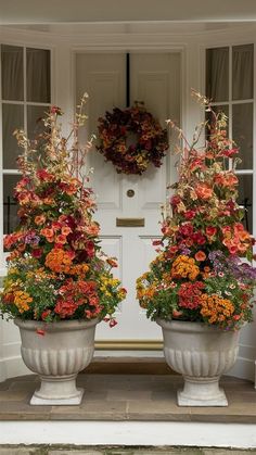 two large flower pots sitting in front of a white door