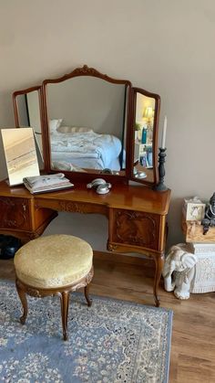 a bedroom with a vanity, mirror and stool on the floor in front of it