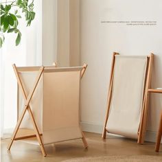 two folding chairs next to each other in front of a white wall and potted plant