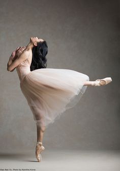 a ballerina in a tutu and ballet shoes is posing for the camera with her arms stretched out