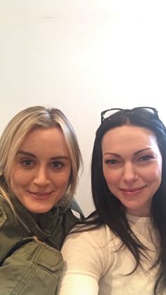 two women sitting next to each other with their arms around one another and smiling at the camera