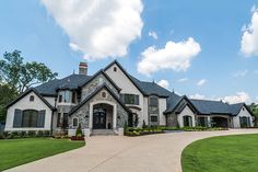 a large white house with lots of windows and landscaping on the front lawn, surrounded by lush green grass