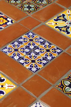 an orange and blue tiled floor with different designs on it's sides, as well as the bottom part of the tile