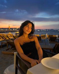 a woman sitting at a table on the beach