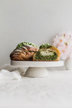 a white cake plate topped with a croissant covered in spinach and cheese