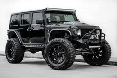 a black jeep parked in front of a white wall