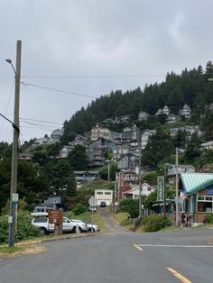 cars are parked on the side of the road in front of a hill with houses