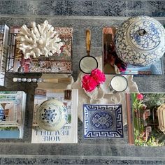 an assortment of decorative items displayed on a table with blue and white designs, flowers, candles, and books