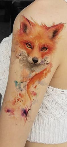 a woman's arm with a watercolor fox tattoo on it