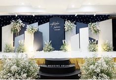 the stage is set up for an event with white flowers and greenery on it