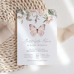 a white and pink butterfly baby shower is on top of a wicker tablecloth