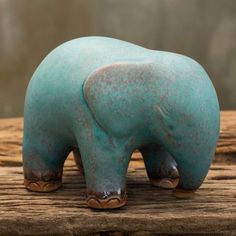 an elephant figurine sitting on top of a piece of wood