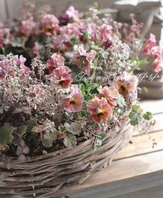 a basket filled with pink flowers sitting on top of a wooden table