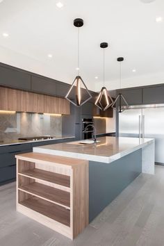 an island in the middle of a kitchen with two pendant lights hanging from it's ceiling