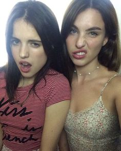 two young women posing for the camera in front of a mirror with their mouths open