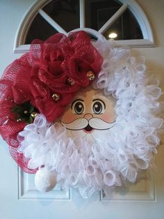 a door hanger with a santa claus face and red flowers on it's head