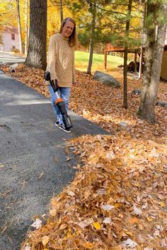 a woman riding a scooter down a leaf covered road