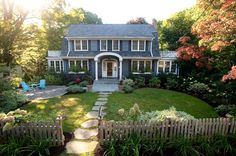 a house that is in the middle of some trees and grass with a walkway leading up to it