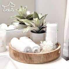 a wooden tray with towels, candles and plants in it on a bathroom countertop