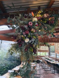 an arrangement of flowers and greenery hangs from the ceiling