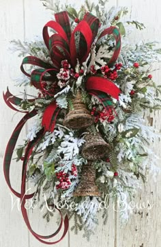 a christmas wreath hanging on the side of a white wooden wall with red and green ribbon