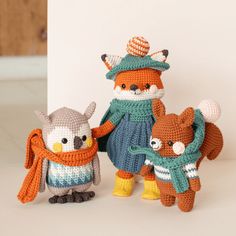 three crocheted stuffed animals standing next to each other on a white table top