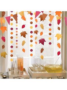 a table topped with drinks and fall leaves hanging from the window sill above it