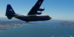 a blue and yellow plane flying over the ocean