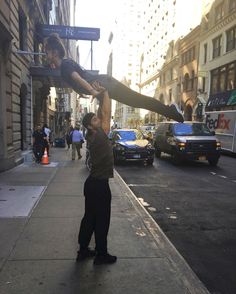 a man holding up an upside down sign on the side of a road in front of tall buildings