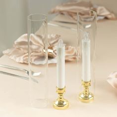 two candles are sitting next to each other on a table in front of some napkins