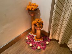 two vases with flowers on the floor next to each other and candles in front of them