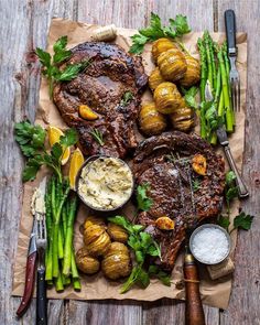 steak, potatoes and asparagus on a piece of parchment paper with knifes