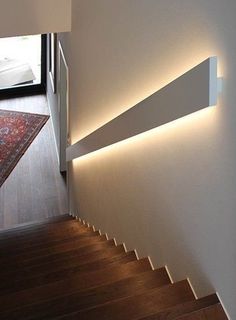 the light is shining on the wall next to the stair case and carpeted floor