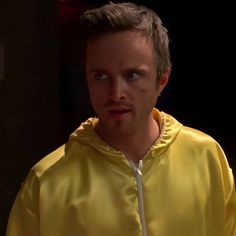 a man in a yellow jacket looking at the camera with an intense look on his face