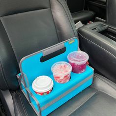 two plastic cups sitting on top of a blue tray in the back seat of a car