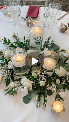 the table is set with white flowers and candles for an elegant centerpiece on top of it