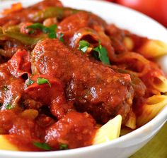 a bowl filled with pasta and meat covered in sauce