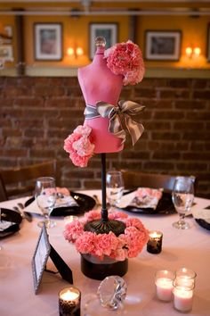 the table is set with pink flowers, candles and an arrangement of mannequins