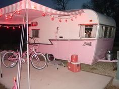 a pink and white trailer parked next to a bike