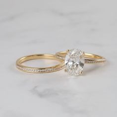 two yellow gold engagement and wedding rings on a white marble countertop, one with a single diamond in the center